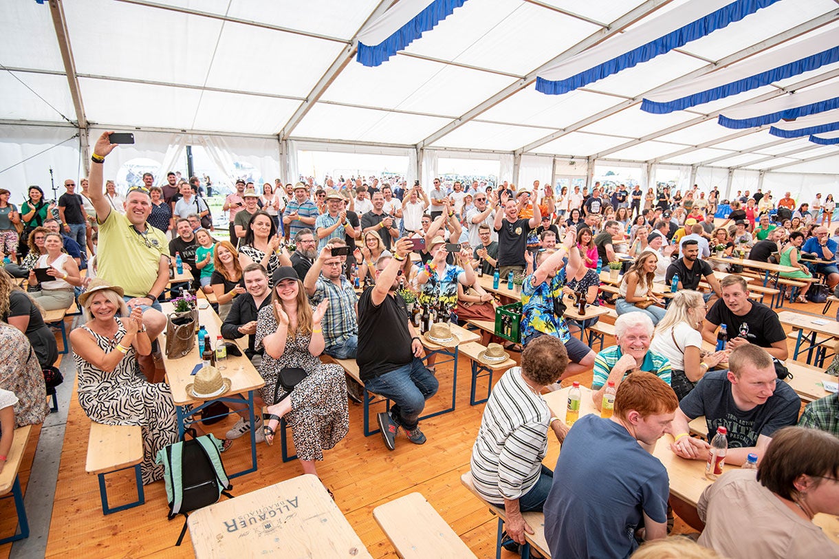 Crowd at Event in Large Tent with Wooden Benches Crowd at Event in Large Tent with Wooden Benches